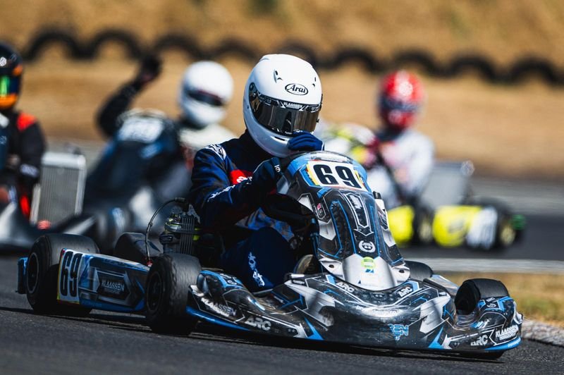 A pack of karts running nose to tail out of a corner.