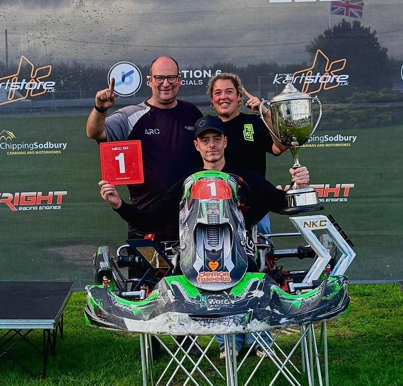 David and Ashley Klaassen with their driver and the kart, celebrating a win at the NKC 2026 championship, trophy and number one plate held up.